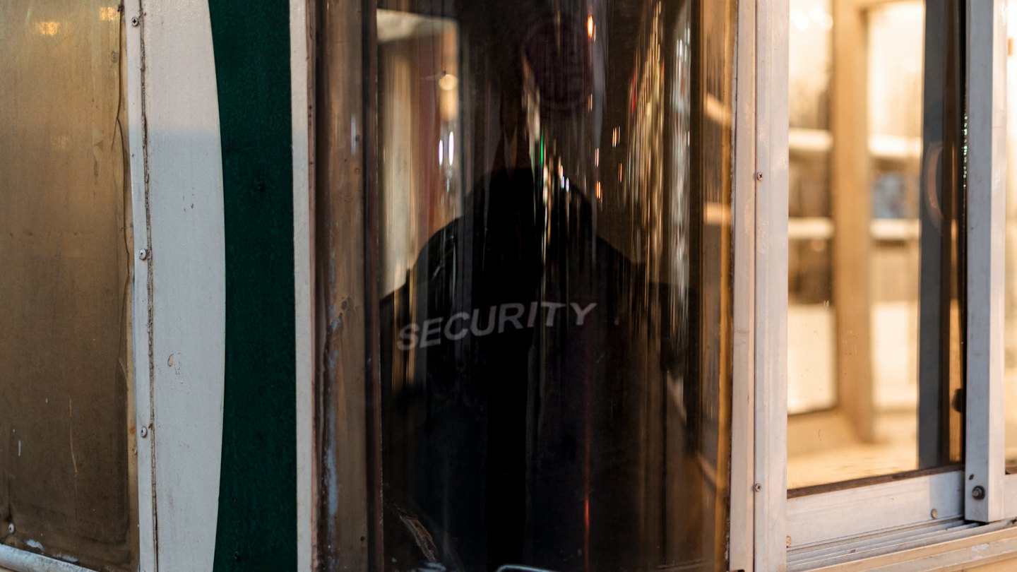 Una guardia di sicurezza in uniforme si trova all'interno di una piccola cabina.
