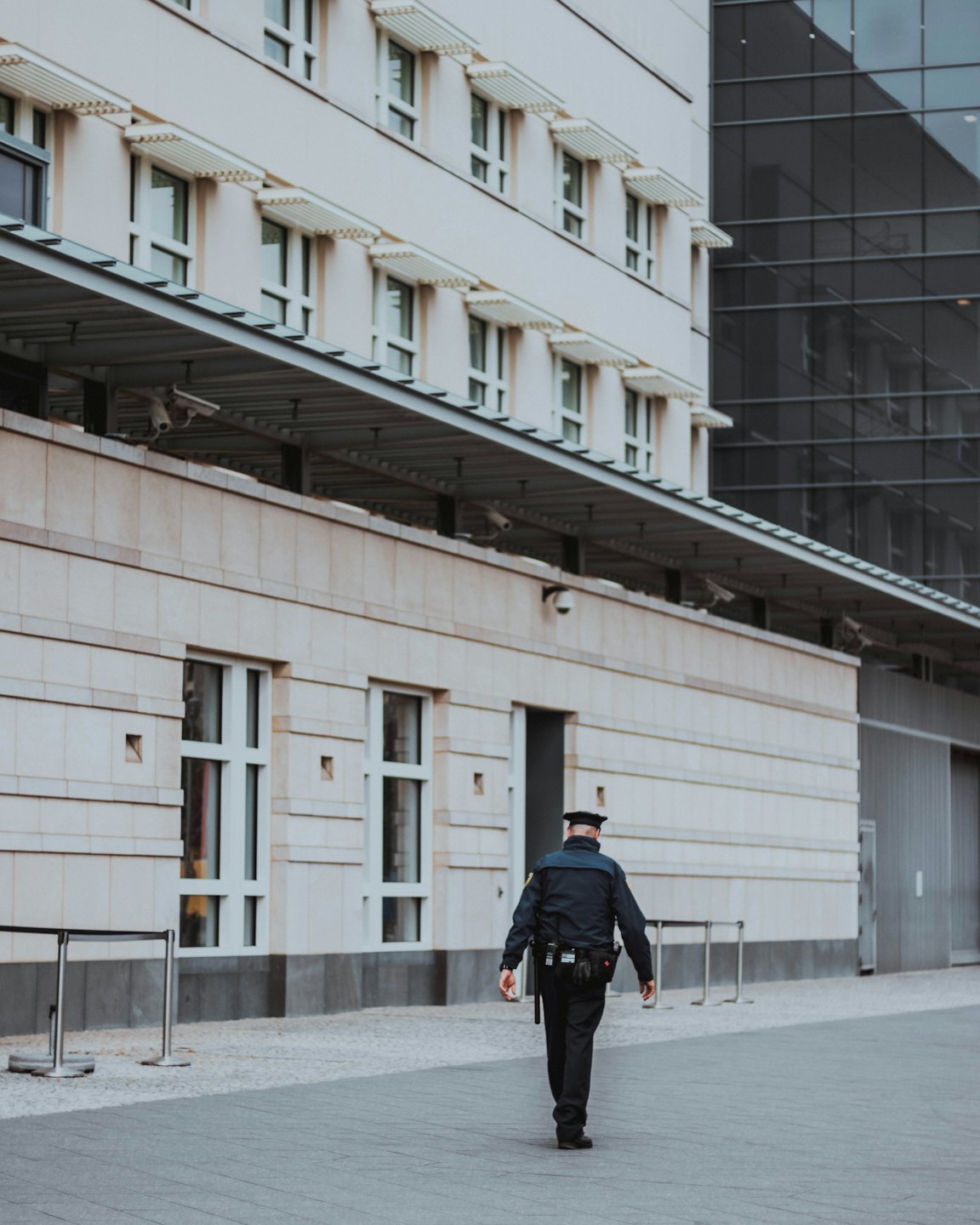 Professionista della sicurezza si allontana da un edificio moderno con telecamere.